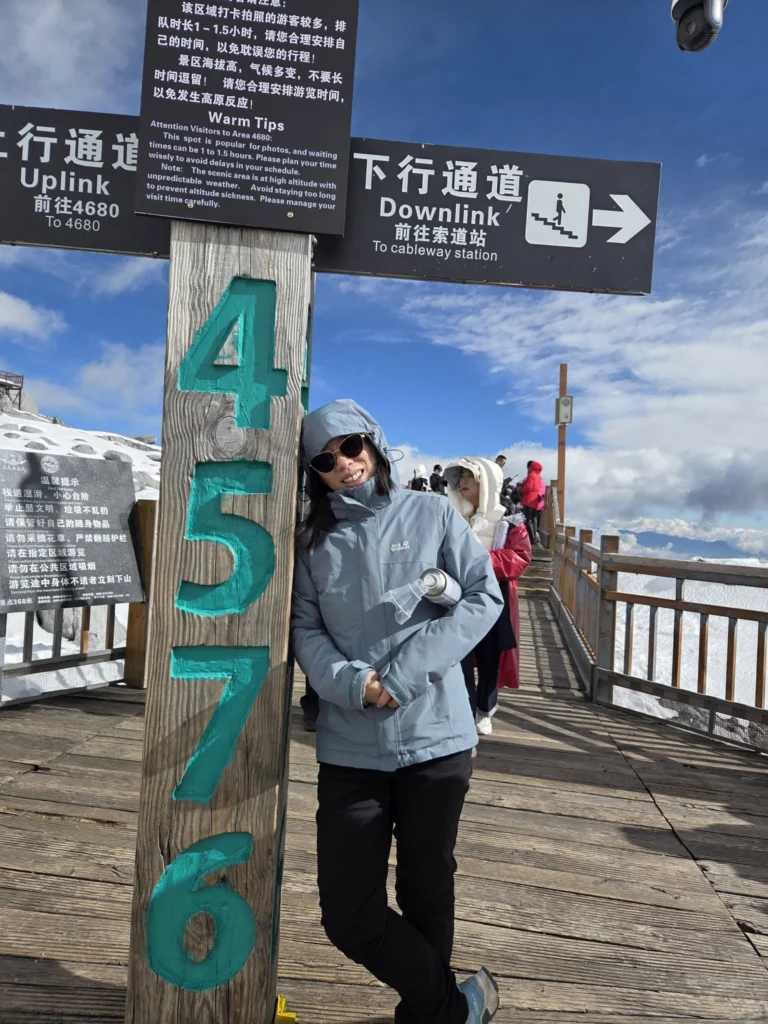 Rong an der oberen Seilbahnstation, angelehnt an einem Schild, dass die Höhe mit 4576 mNN angibt