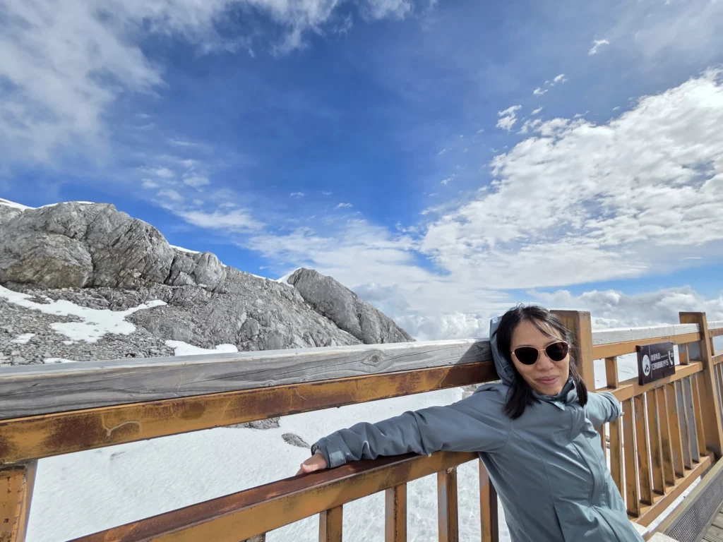 Rong, auf einer Bank sitzend mit einem bergigen Hintergrund